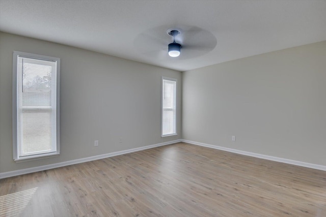 unfurnished room featuring light wood finished floors, baseboards, and plenty of natural light
