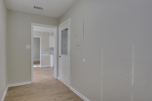 hall featuring visible vents, baseboards, and light wood-type flooring