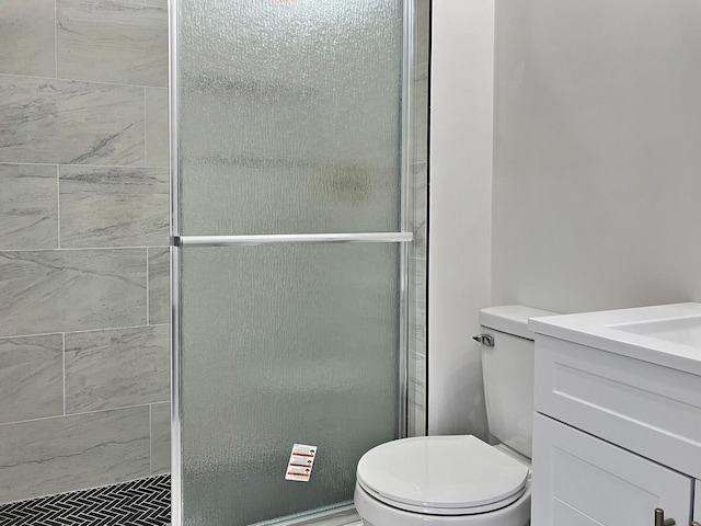 bathroom featuring vanity, toilet, and a shower with door