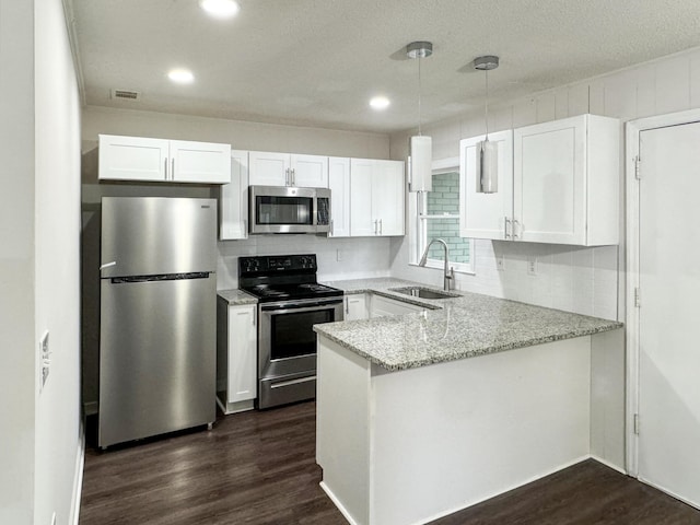 kitchen featuring white cabinets, sink, appliances with stainless steel finishes, light stone counters, and kitchen peninsula