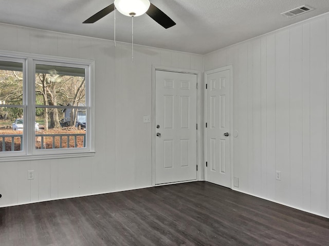 unfurnished room with ceiling fan, wooden walls, dark wood-type flooring, and a textured ceiling