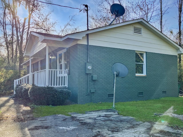 view of side of home featuring a porch and a yard