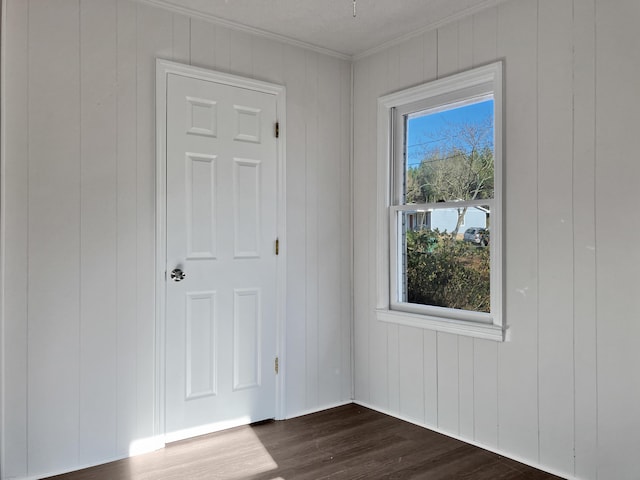 unfurnished room with crown molding, dark hardwood / wood-style flooring, and wood walls