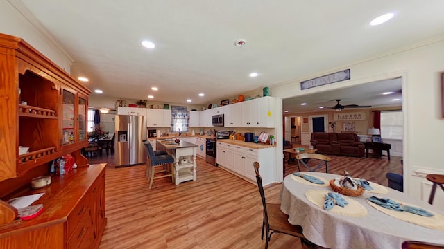 dining space with ceiling fan, light wood-style flooring, recessed lighting, and ornamental molding