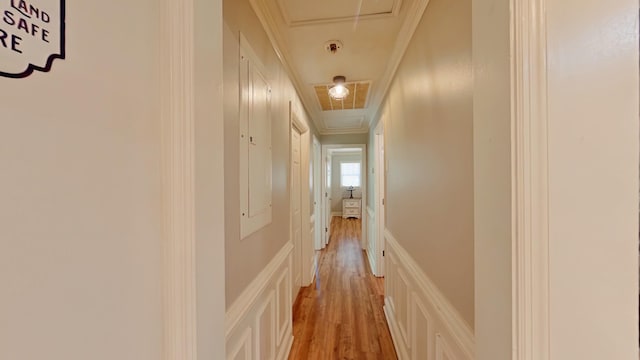 corridor featuring light wood-style flooring, attic access, and ornamental molding