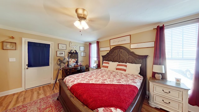 bedroom with a ceiling fan, crown molding, wood finished floors, and baseboards