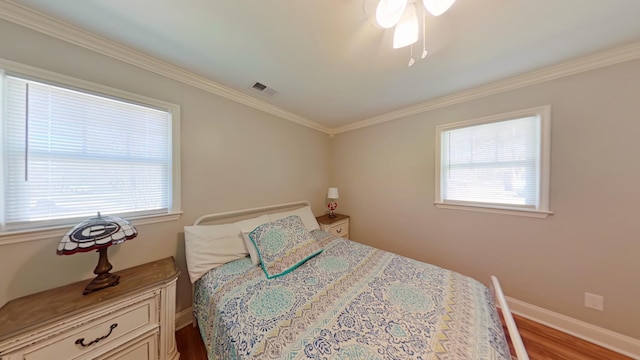 bedroom featuring multiple windows, wood finished floors, visible vents, and baseboards