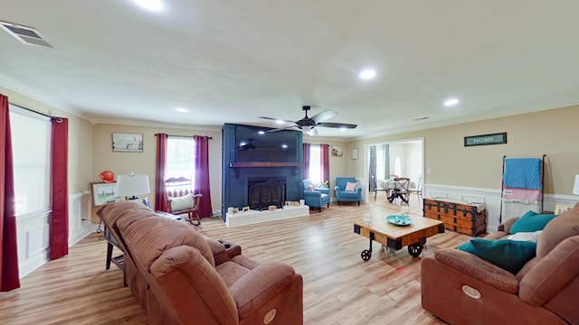 living area with light wood-style floors, a ceiling fan, and ornamental molding