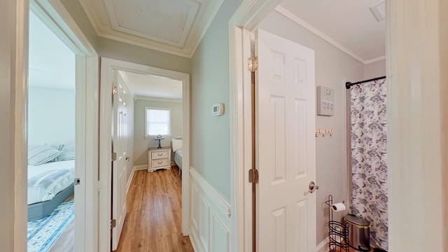 corridor with light wood finished floors, attic access, and crown molding