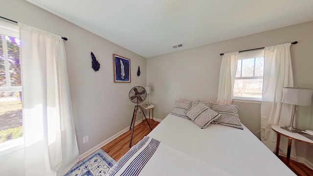 bedroom featuring visible vents, baseboards, and wood finished floors