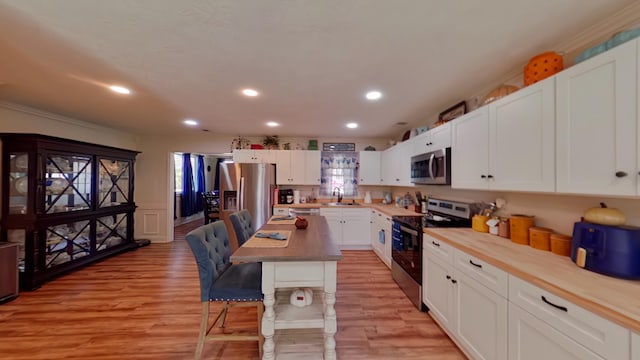 kitchen with a sink, a kitchen breakfast bar, light wood finished floors, and stainless steel appliances