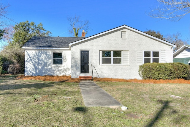 view of front of house featuring a front yard, brick siding, a chimney, and entry steps