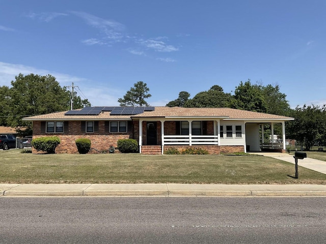 single story home featuring a front lawn, covered porch, and solar panels