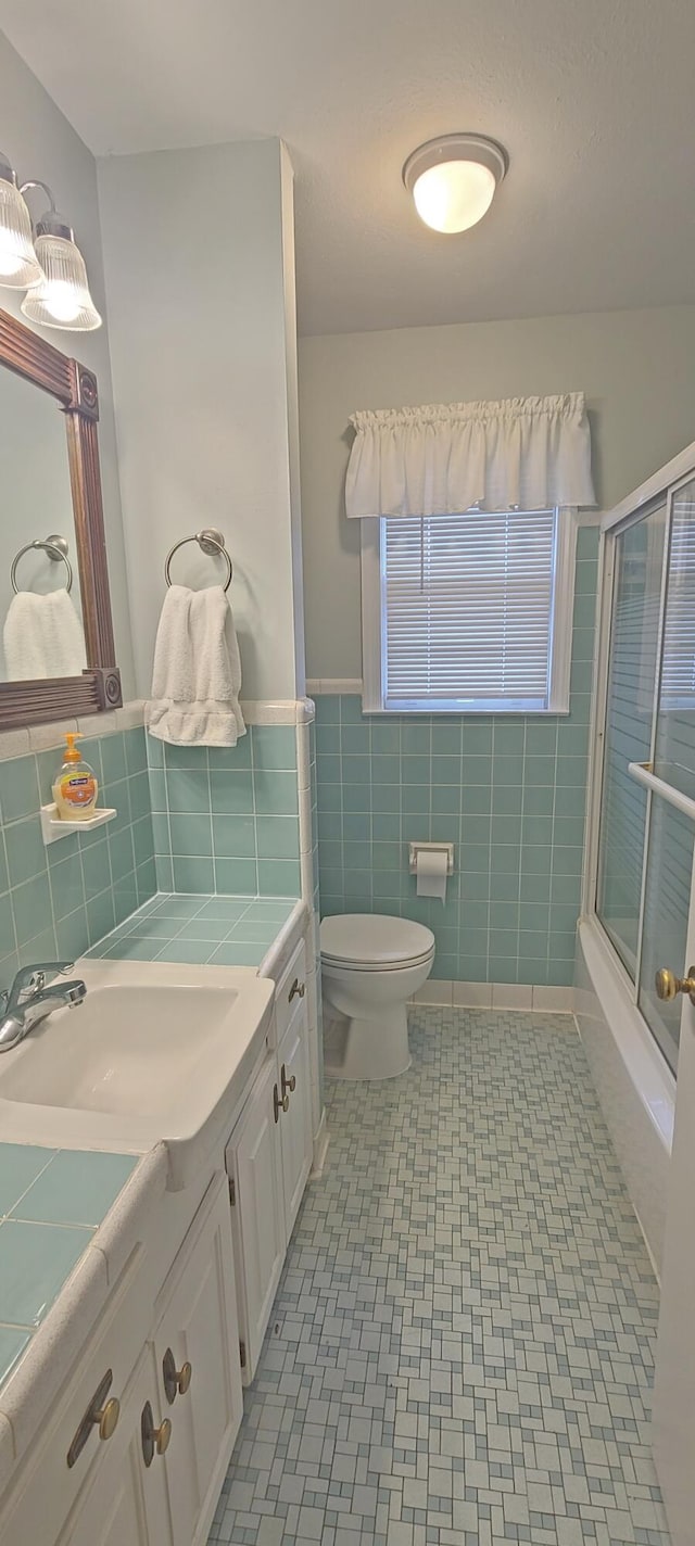 bathroom with walk in shower, tile patterned flooring, toilet, vanity, and tile walls