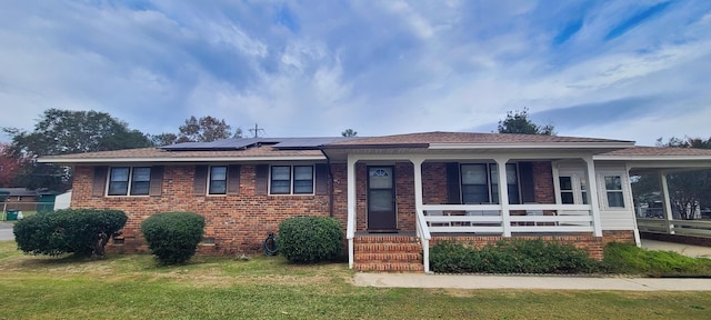 view of front facade featuring a front lawn, covered porch, and solar panels