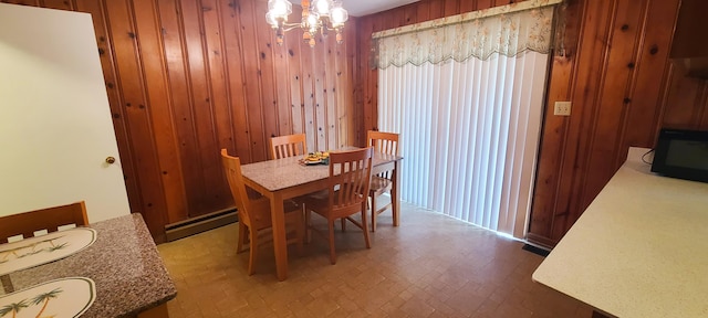 dining space featuring a chandelier, wood walls, and a baseboard heating unit