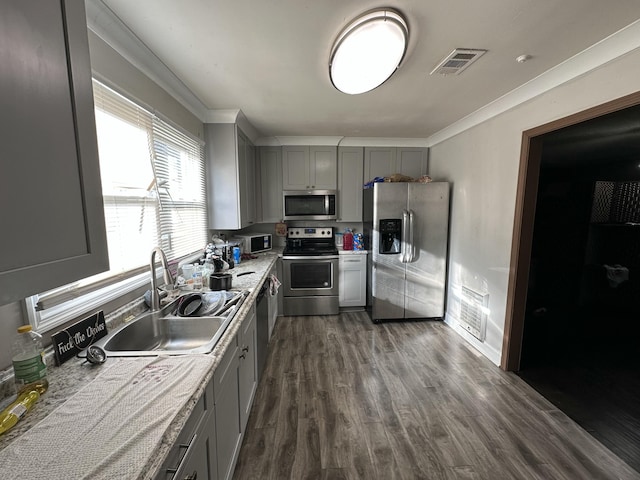 kitchen with gray cabinetry, sink, stainless steel appliances, dark hardwood / wood-style flooring, and ornamental molding