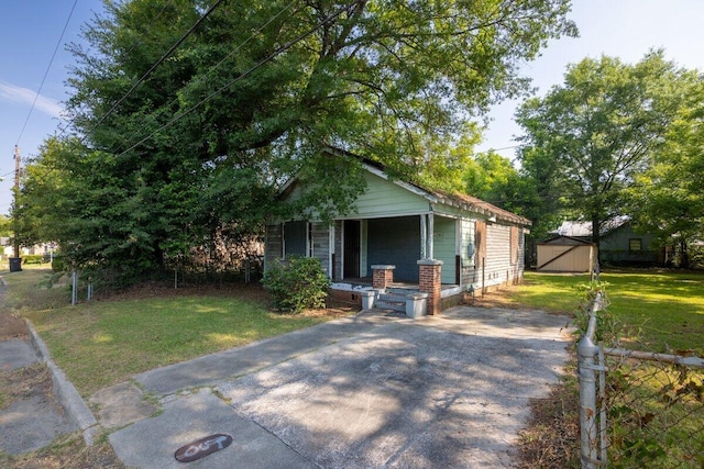 view of front of home with a porch, a storage shed, and a front lawn