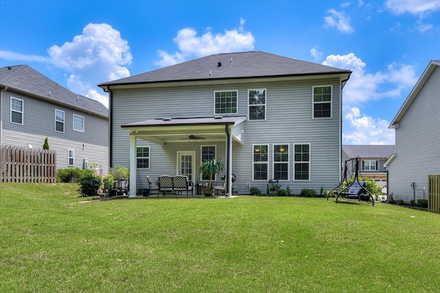 back of house with ceiling fan and a yard