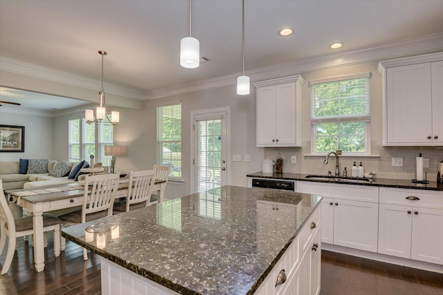 kitchen with dark stone counters, white cabinets, sink, decorative light fixtures, and a kitchen island