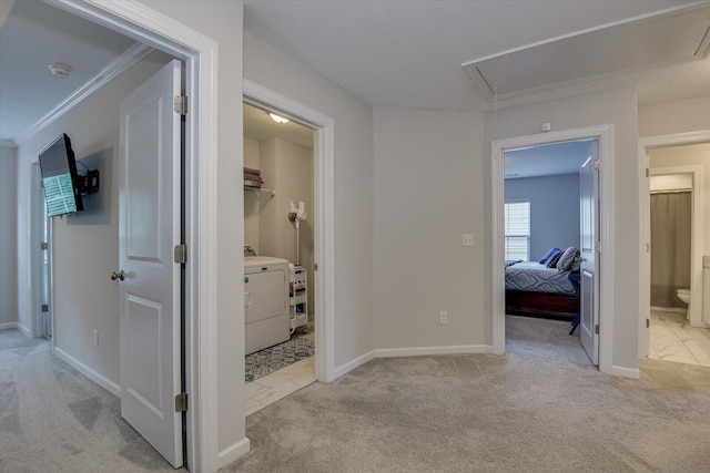 hall with light colored carpet, ornamental molding, and washer / clothes dryer