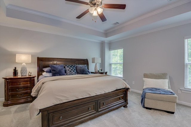 bedroom with a raised ceiling, ceiling fan, light colored carpet, and ornamental molding