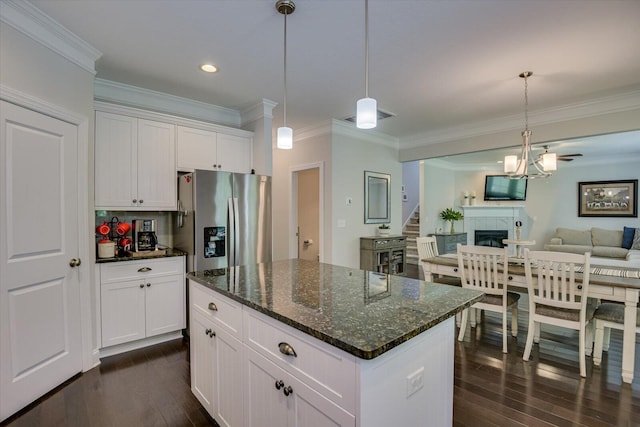 kitchen with pendant lighting, a tile fireplace, dark stone counters, white cabinets, and stainless steel refrigerator with ice dispenser