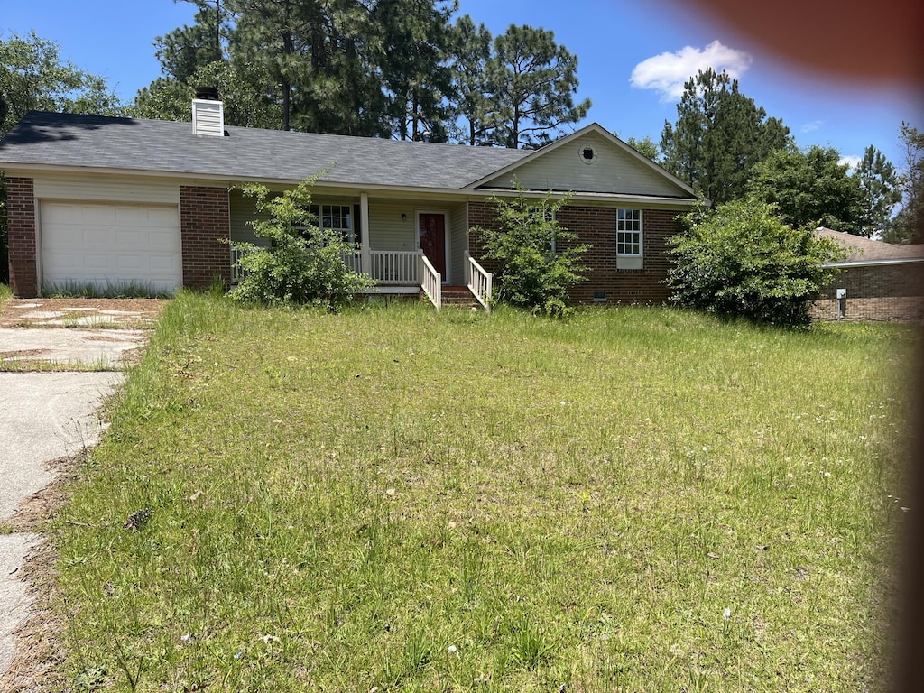 ranch-style house with a garage, a front yard, brick siding, and driveway