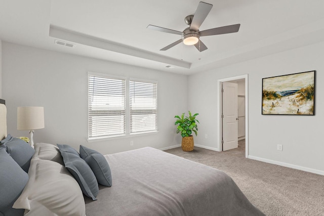 carpeted bedroom featuring baseboards, visible vents, ceiling fan, and a tray ceiling