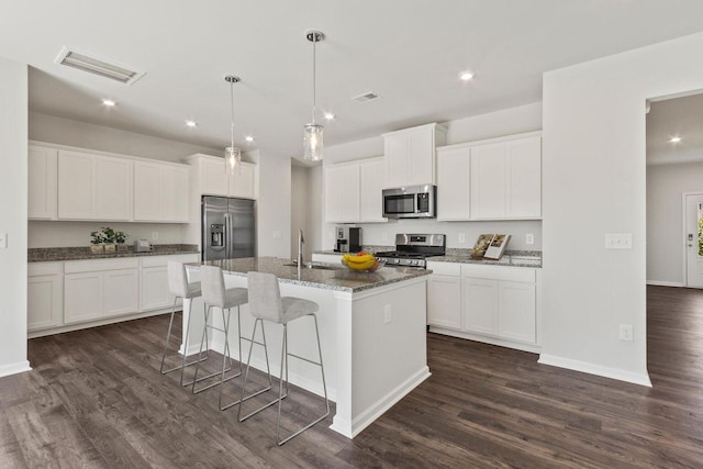 kitchen featuring visible vents, a kitchen island with sink, appliances with stainless steel finishes, and dark wood-type flooring