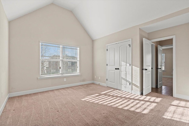 unfurnished bedroom featuring light carpet, a closet, and vaulted ceiling