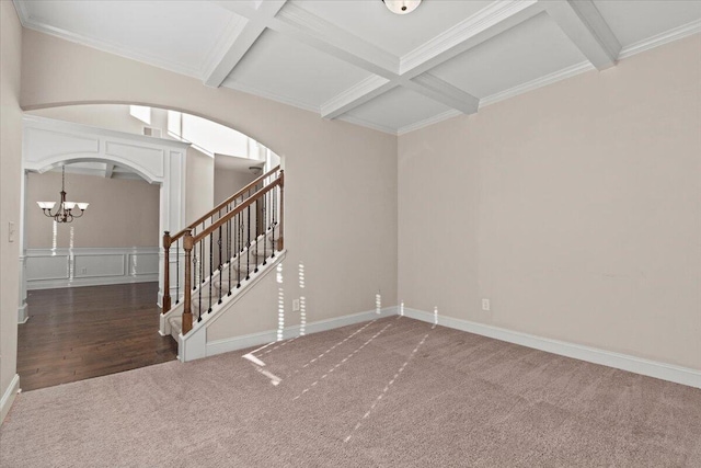 carpeted spare room with beam ceiling, crown molding, an inviting chandelier, and coffered ceiling