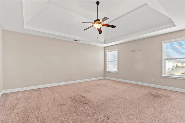 carpeted spare room featuring a raised ceiling and ceiling fan