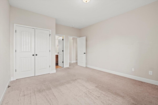 unfurnished bedroom with light colored carpet and a closet