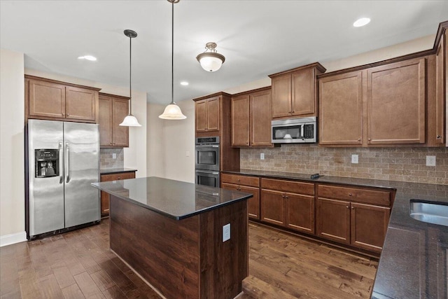 kitchen featuring stainless steel appliances, dark hardwood / wood-style floors, a kitchen island, and decorative light fixtures