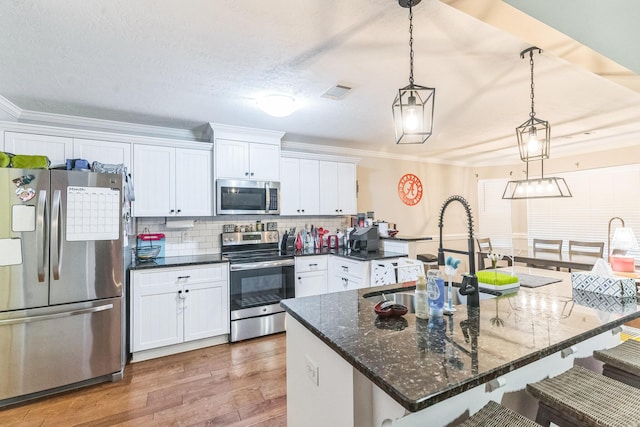 7105 Summerton Dr, Augusta, GA 30909 - kitchen featuring white cabinetry, a breakfast bar, appliances with stainless steel finishes, wood finished floors, and backsplash