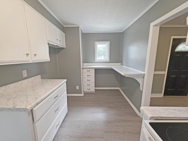 1005 Weston St, North Augusta, SC 29841 - kitchen featuring light wood-style floors, light countertops, a textured ceiling, white cabinetry, and crown molding