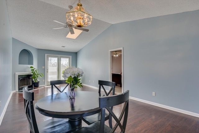 dining area with a fireplace, ceiling fan, vaulted ceiling, wood finished floors, and baseboards