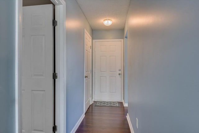 hall with baseboards, dark wood-type flooring, and a textured ceiling