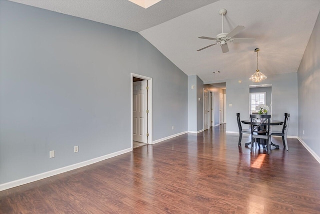 interior space featuring ceiling fan with notable chandelier, wood finished floors, lofted ceiling, and baseboards