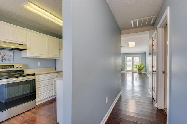 hall with dark wood-style floors, baseboards, visible vents, and a textured ceiling