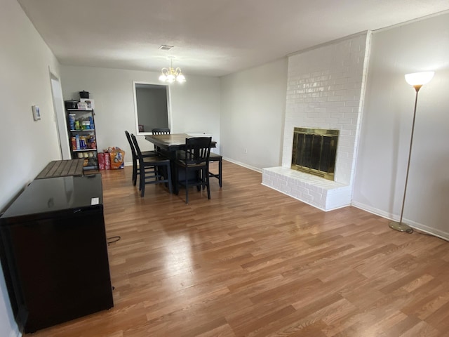 3406 Pine Hill Rd, Hephzibah, GA 30815 - dining space with light wood-style floors, baseboards, a brick fireplace, and a notable chandelier