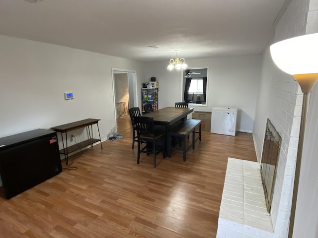 3406 Pine Hill Rd, Hephzibah, GA 30815 - dining space with light wood-type flooring, baseboards, a brick fireplace, and a chandelier