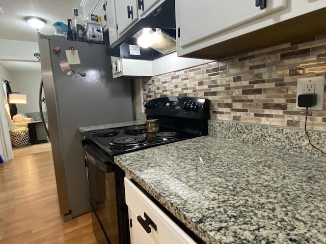 3406 Pine Hill Rd, Hephzibah, GA 30815 - kitchen with black electric range, light wood-style flooring, stone counters, tasteful backsplash, and under cabinet range hood