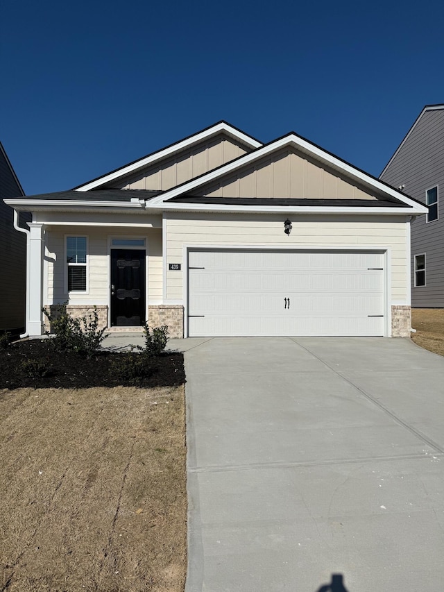 craftsman-style house featuring a garage, stone siding, board and batten siding, and driveway