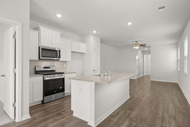 kitchen with decorative backsplash, stainless steel appliances, sink, a center island with sink, and white cabinetry