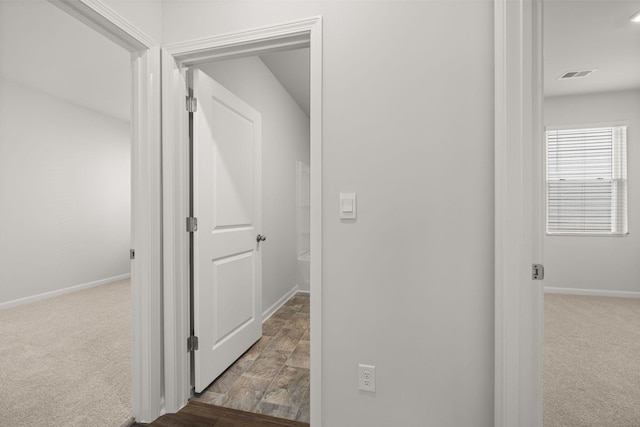 corridor featuring carpet, visible vents, and baseboards