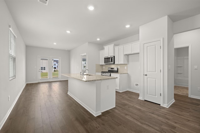 kitchen with appliances with stainless steel finishes, a kitchen island with sink, sink, dark hardwood / wood-style floors, and white cabinetry