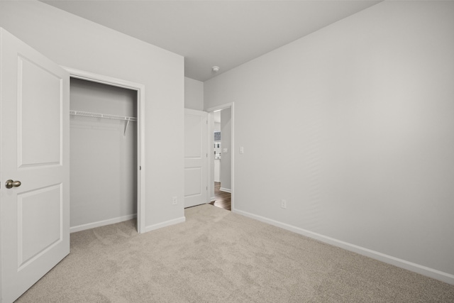 unfurnished bedroom featuring baseboards, carpet floors, and a closet