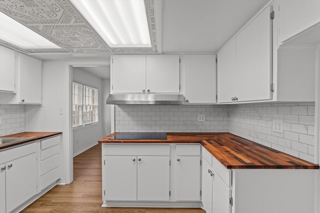 4004 Columbia Rd, Martinez, GA 30907 - kitchen with under cabinet range hood, wood counters, black electric cooktop, white cabinets, and light wood-style flooring